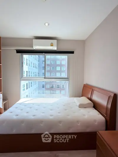 Bright bedroom with large window and modern furnishings in urban apartment.
