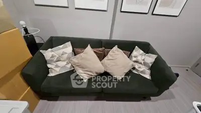 Cozy living room with stylish dark green sofa and decorative pillows, perfect for relaxation.