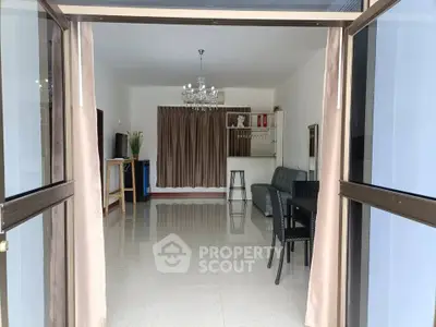 Spacious living room with elegant chandelier and glossy tiled flooring, perfect for modern living.