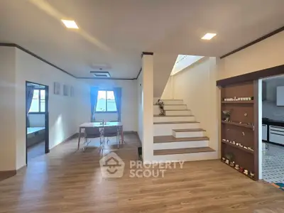 Spacious modern living area with wooden flooring and elegant staircase