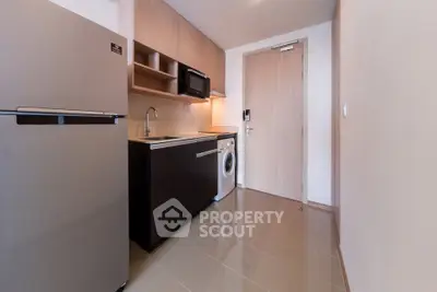 Modern compact kitchen with sleek appliances and stylish cabinetry in a contemporary apartment.