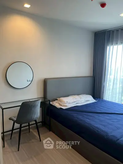 Modern bedroom with stylish decor and large window offering natural light.