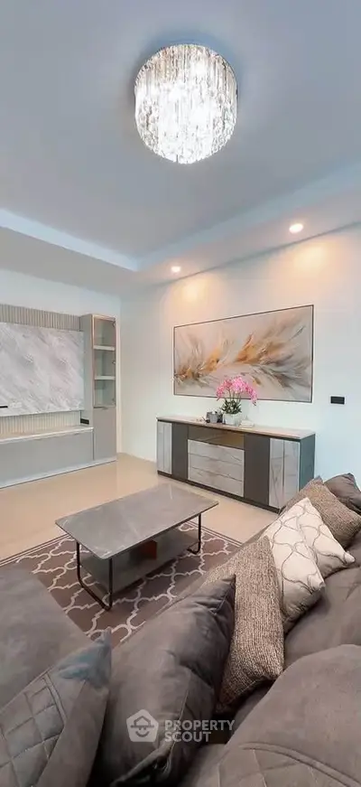 Elegant living room with modern decor, plush sofa, stylish coffee table, and chic lighting fixture.