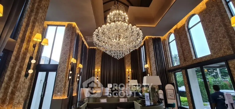 Luxurious living room with grand chandelier and elegant decor, featuring tall windows and plush seating.