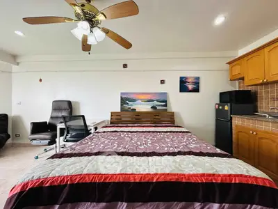 Cozy studio apartment with bed, desk, and kitchenette, ideal for modern living.