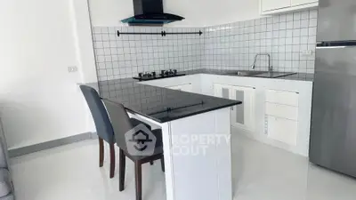 Modern kitchen with sleek black countertops and gas stove in a stylish apartment.