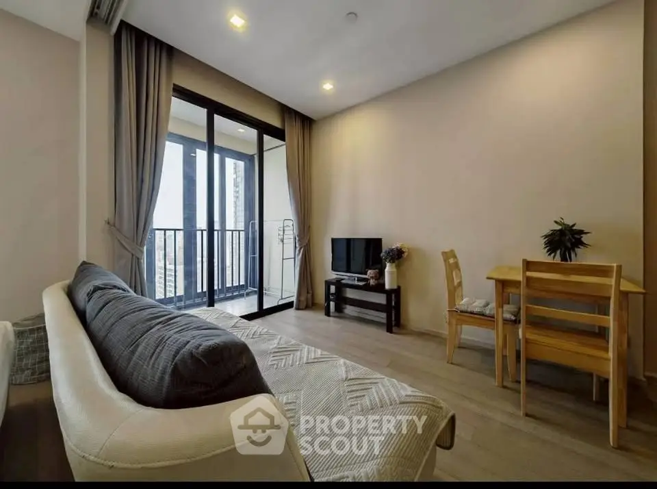 Modern living room with balcony view, cozy seating, and dining area in a stylish apartment.
