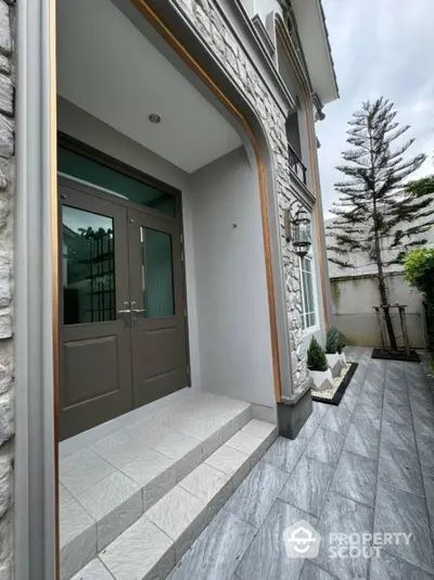 Elegant entrance of modern home with stone facade and stylish landscaping