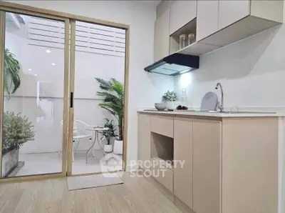 Modern kitchen with sliding glass doors leading to a cozy patio area, featuring sleek cabinetry and elegant decor.