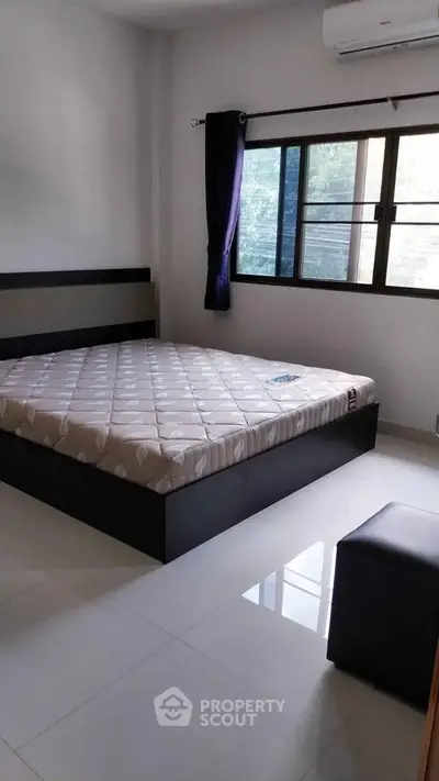 Spacious bedroom with large window and modern furnishings in a bright apartment.