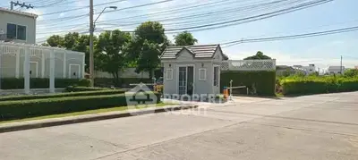 Charming gated entrance of a residential community with lush greenery and clear skies.