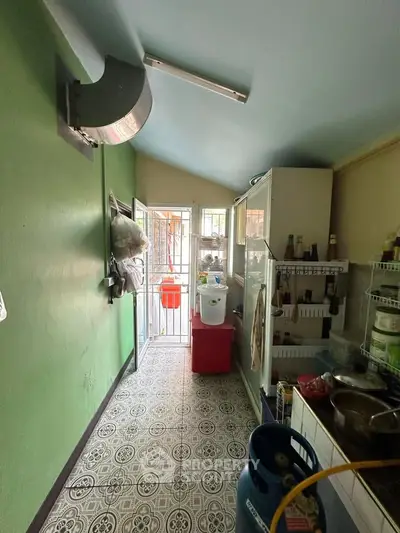 Charming narrow kitchen with colorful walls and patterned floor tiles, featuring open shelving and natural light.
