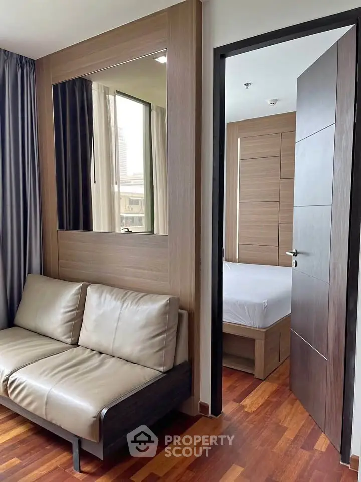 Modern apartment interior with cozy living room and glimpse of bedroom, featuring wooden flooring and sleek design.