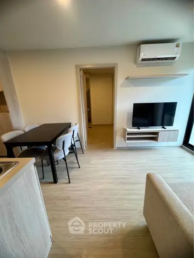 Modern living room with dining area and air conditioning, featuring sleek furniture and wooden flooring.