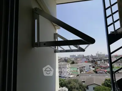 Urban balcony view with metal clothes drying rack and cityscape backdrop.