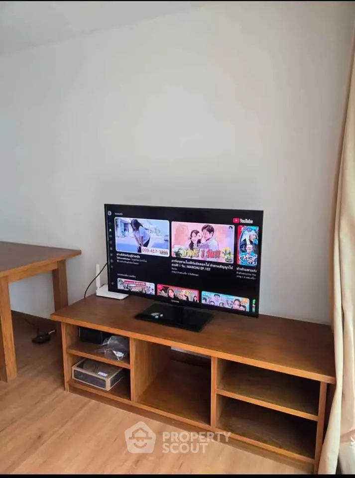 Modern living room with wooden TV stand and flat-screen television, showcasing a cozy and stylish interior.