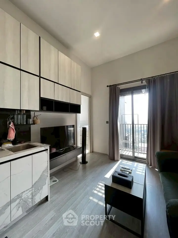 Modern living room with sleek cabinetry and balcony access, featuring stylish decor and natural light.