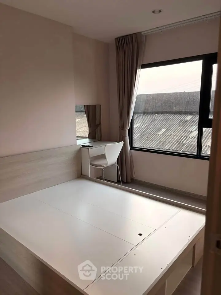 Modern bedroom with large window and minimalist furniture, offering ample natural light and a serene atmosphere.