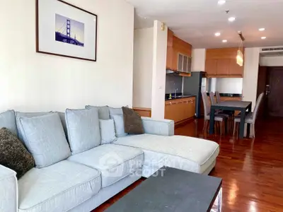 Spacious living room with modern kitchen in open layout, featuring elegant wooden flooring and stylish furniture.