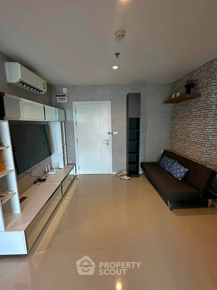 Modern living room with sleek furniture and stylish decor, featuring a wall-mounted TV and air conditioning.
