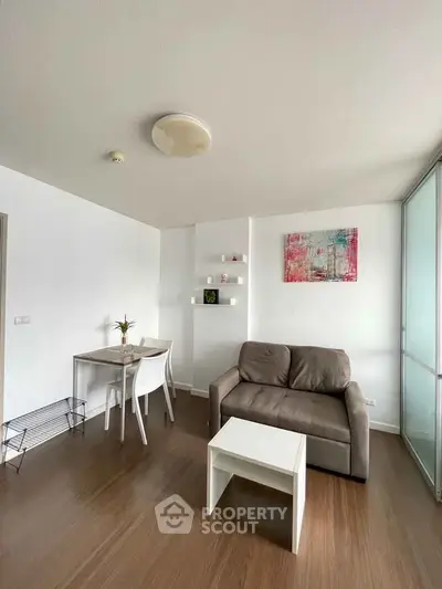 Modern living room with stylish sofa and dining area, featuring contemporary decor and sleek wooden flooring.