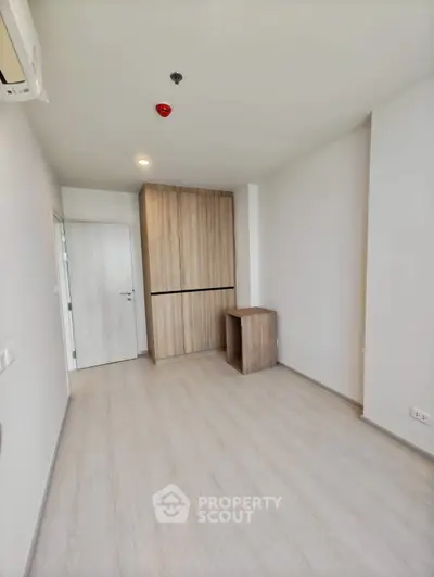 Spacious minimalist room with wooden flooring and built-in wardrobe, perfect for modern living.