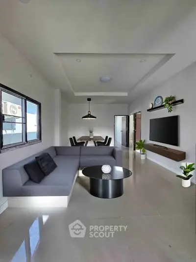 Modern living room with sleek furniture and wall-mounted TV, open layout design.