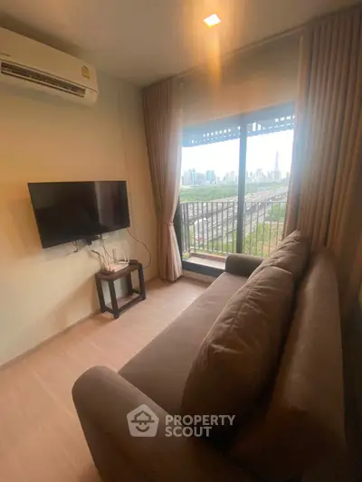 Cozy living room with city view, featuring a sofa, wall-mounted TV, and large window.