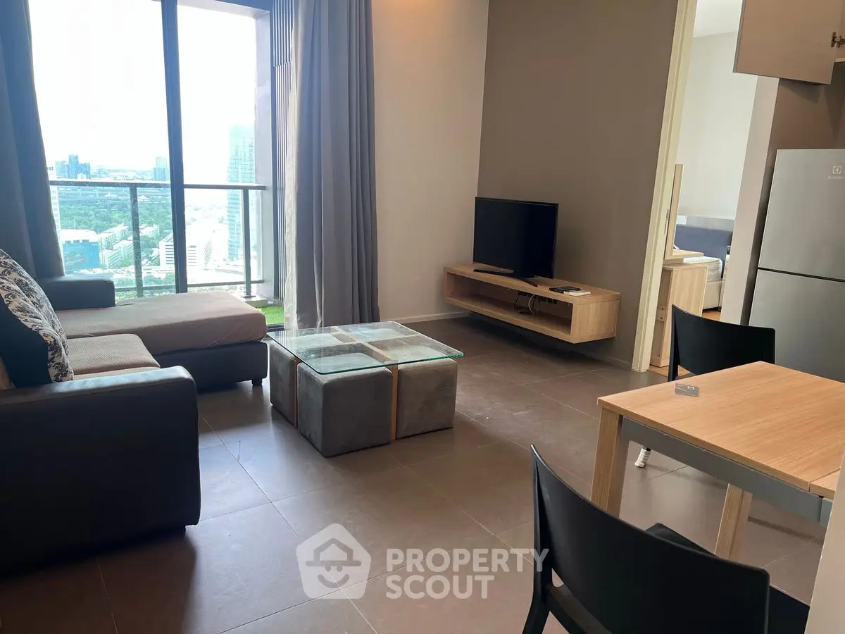 Modern living room with city view, sleek furniture, and open layout in high-rise apartment.
