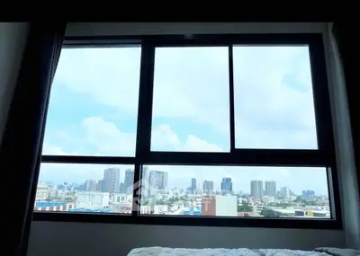 Stunning cityscape view from a high-rise apartment window, showcasing urban skyline and blue skies.