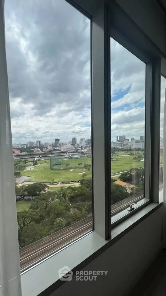 Stunning cityscape view from a high-rise window, showcasing lush greenery and urban skyline.