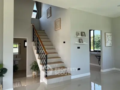 Modern interior with staircase and bright natural light, showcasing elegant decor and spacious design.