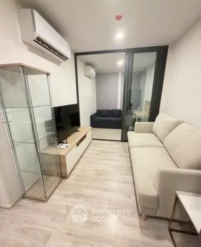 Modern living room with sleek furniture and glass cabinet in a cozy apartment setting.