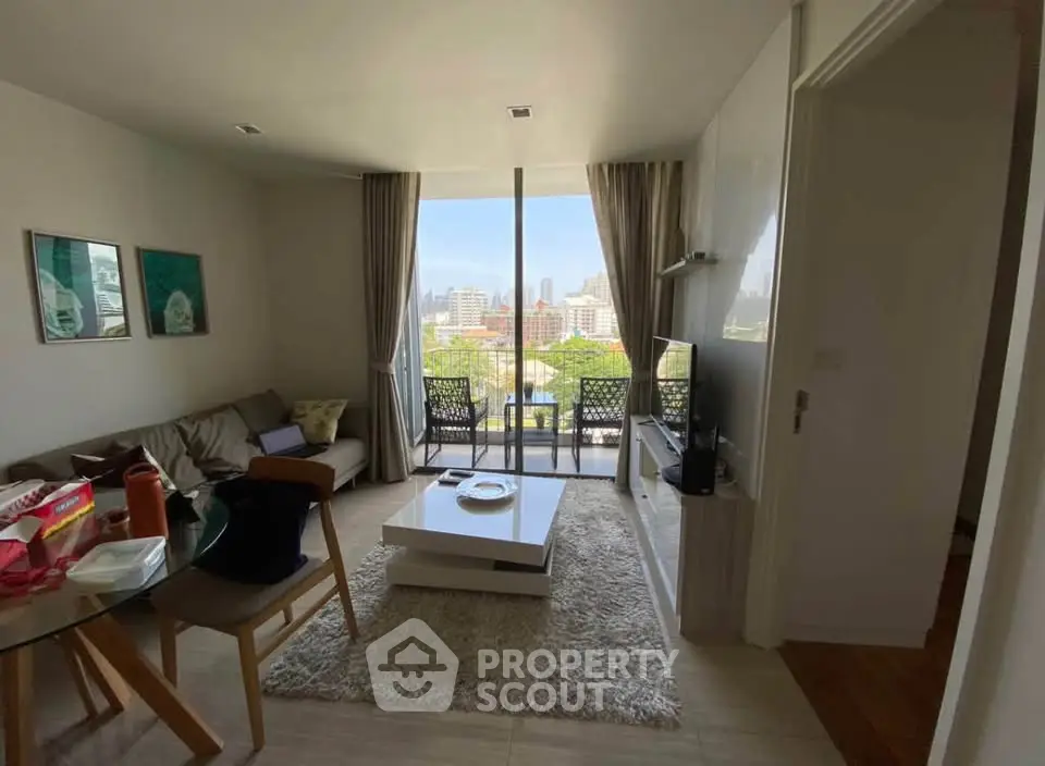 Modern living room with city view, stylish decor, and balcony access in a high-rise apartment.