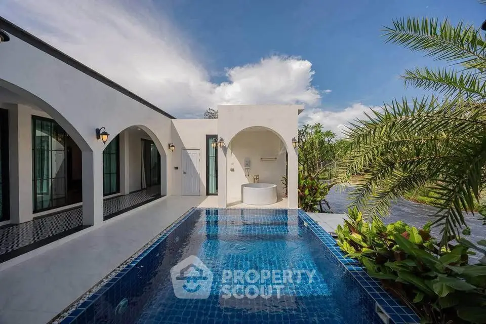 Luxurious villa with private pool and elegant arches, surrounded by lush greenery and serene water views.