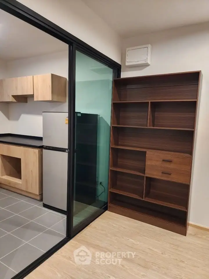 Modern kitchen with sleek cabinetry and glass partition, featuring a stylish wooden bookshelf.