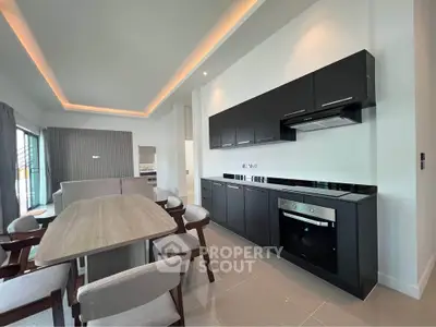Modern open kitchen with sleek black cabinets and dining area in stylish apartment