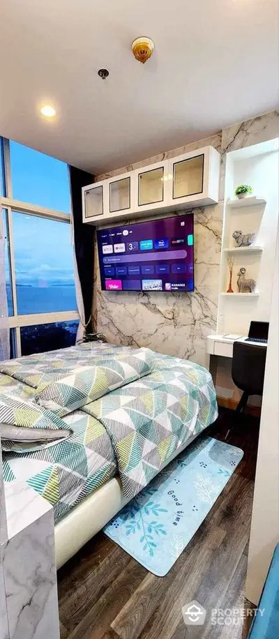 Modern bedroom with ocean view, featuring a wall-mounted TV and sleek decor.