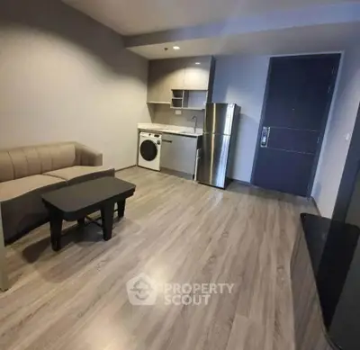 Modern studio apartment with sleek kitchen and cozy living area, featuring stylish flooring and contemporary furniture.