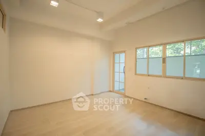 Spacious empty room with wooden flooring and large windows for natural light.