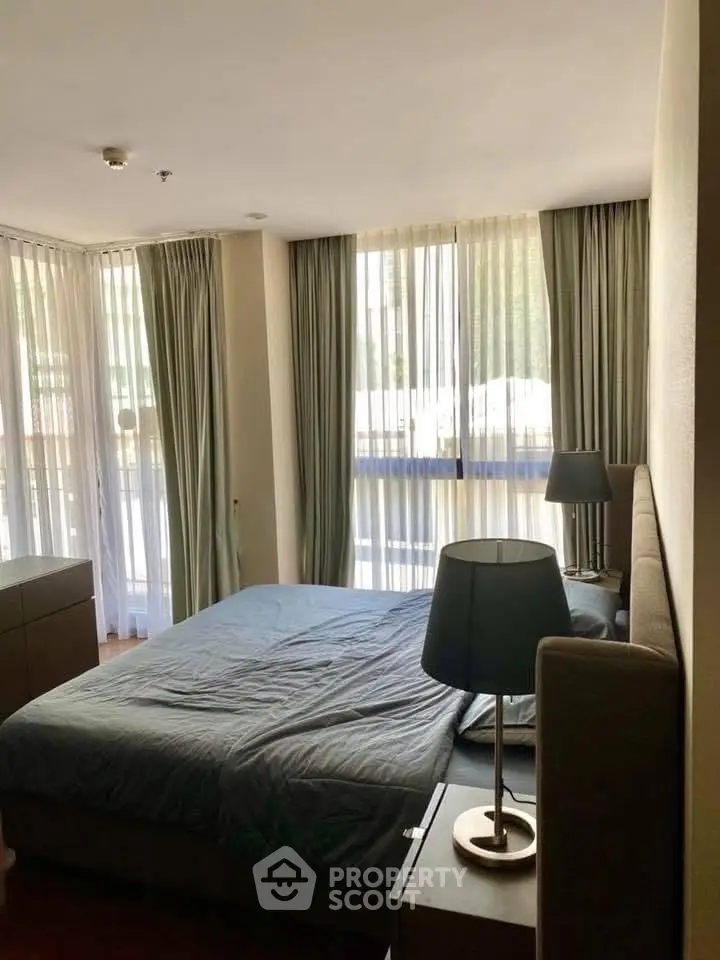 Spacious bedroom with large windows and elegant curtains in a modern apartment.