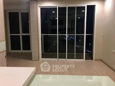 Modern apartment interior with large sliding glass doors and night view.