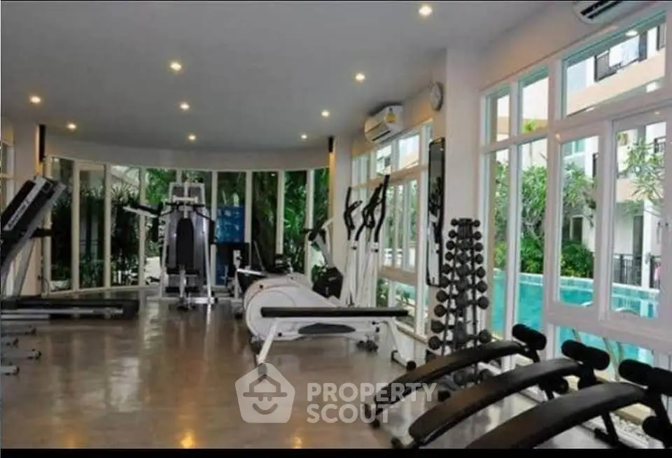 Modern gym with large windows and pool view in luxury apartment complex