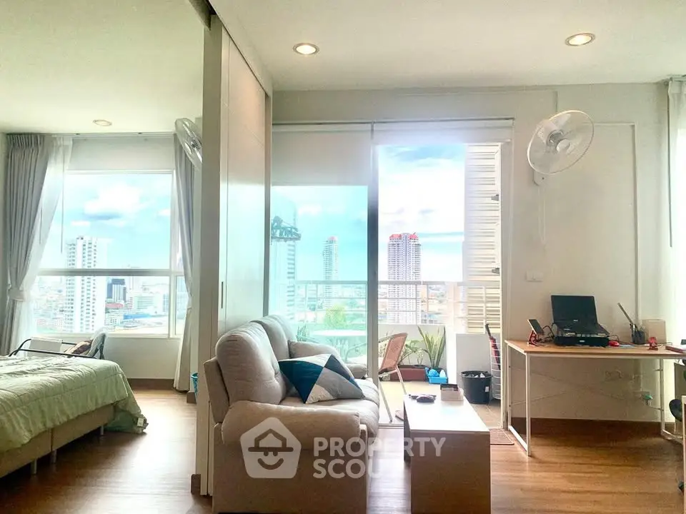 Modern studio apartment with large windows and city view, featuring cozy living area and balcony access.