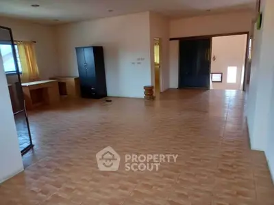 Spacious open-plan living area with tiled flooring and ample natural light.