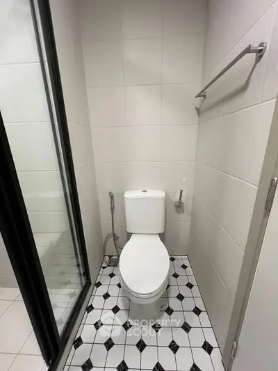 Modern bathroom with sleek design and tiled flooring, featuring a toilet and shower area.