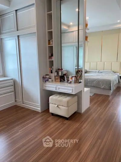 Spacious bedroom with elegant wooden flooring and modern vanity area.
