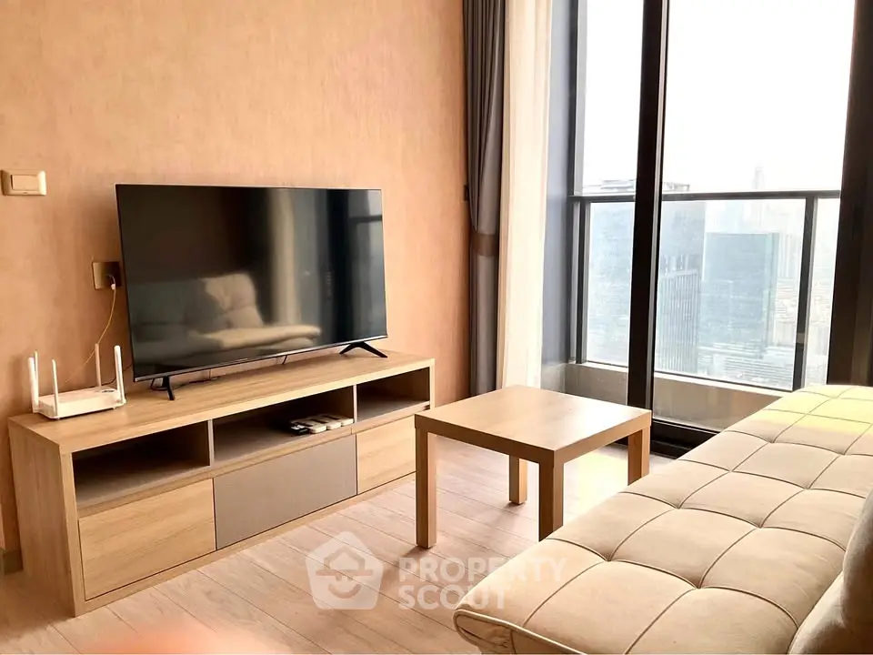 Modern living room with large TV and city view balcony in high-rise apartment.