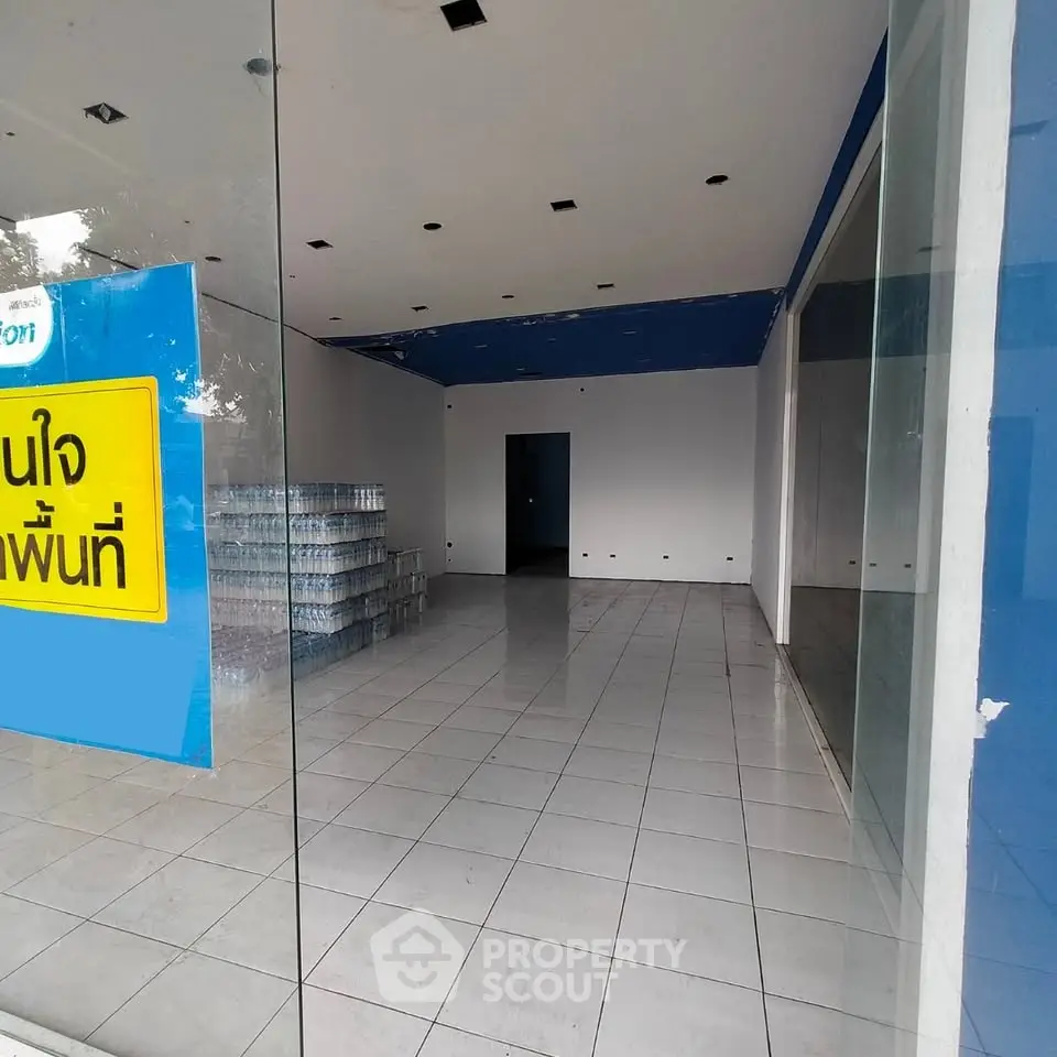 Spacious empty commercial space with tiled flooring and glass facade, ideal for retail or office setup.