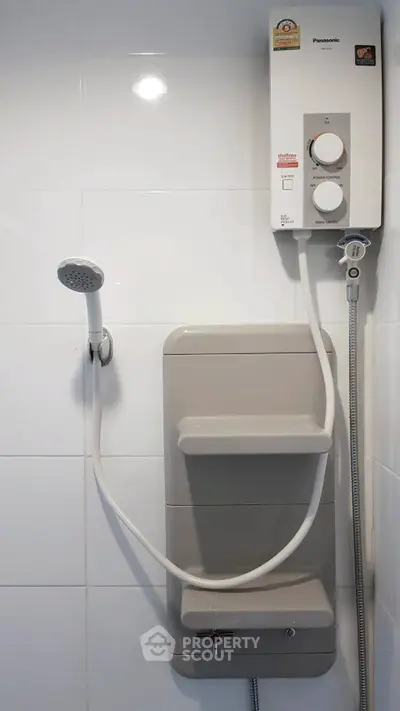 Modern bathroom with shower and water heater, sleek white tiles.